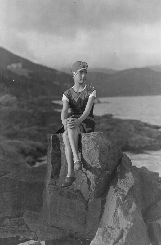 Woman in swimsuit sitting on a rock. By P.S. Foo, circa 1935.